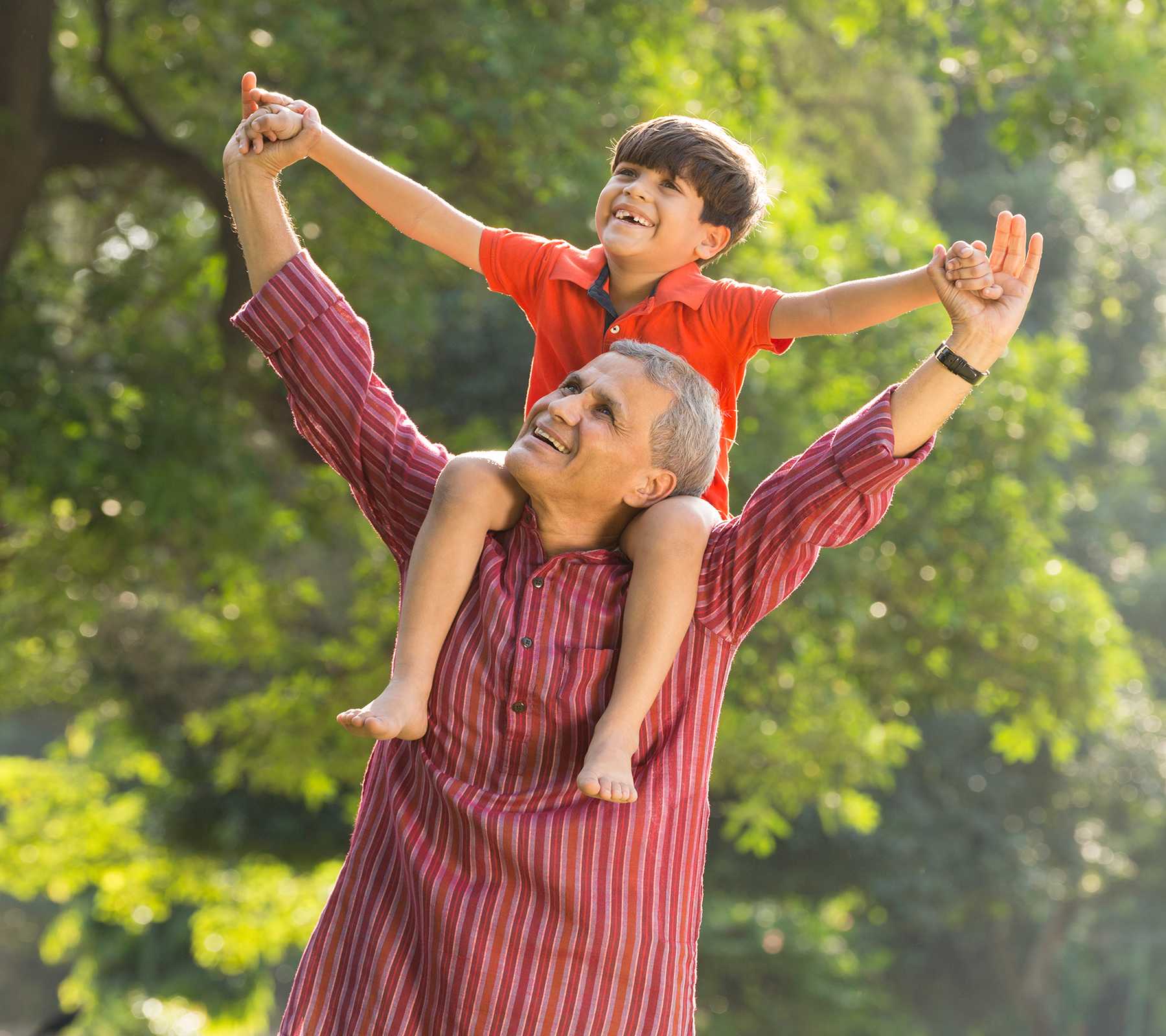 A smiling grandfather gives his grandson a shoulder ride.