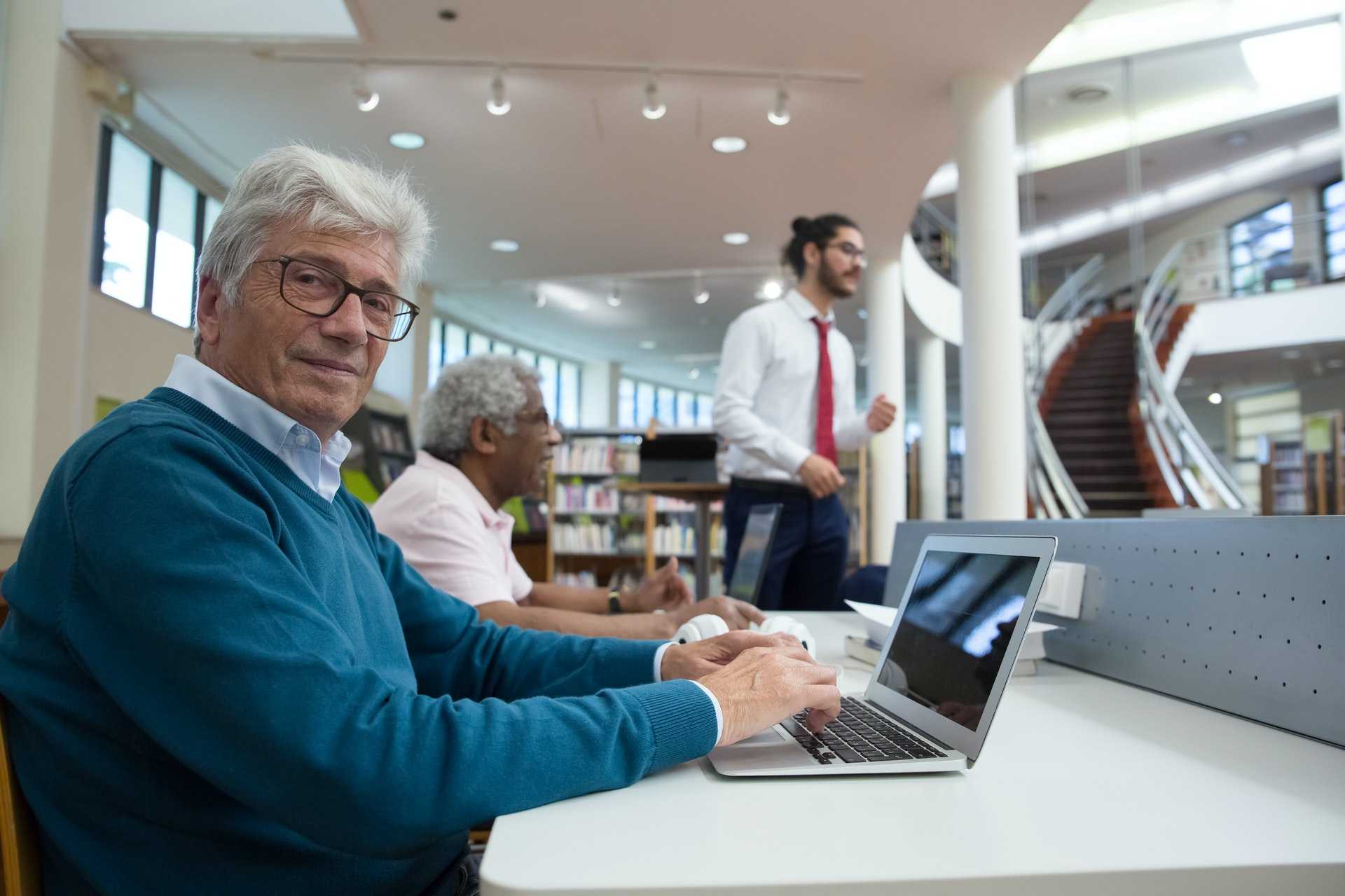 An older man using a laptop while in class in the library