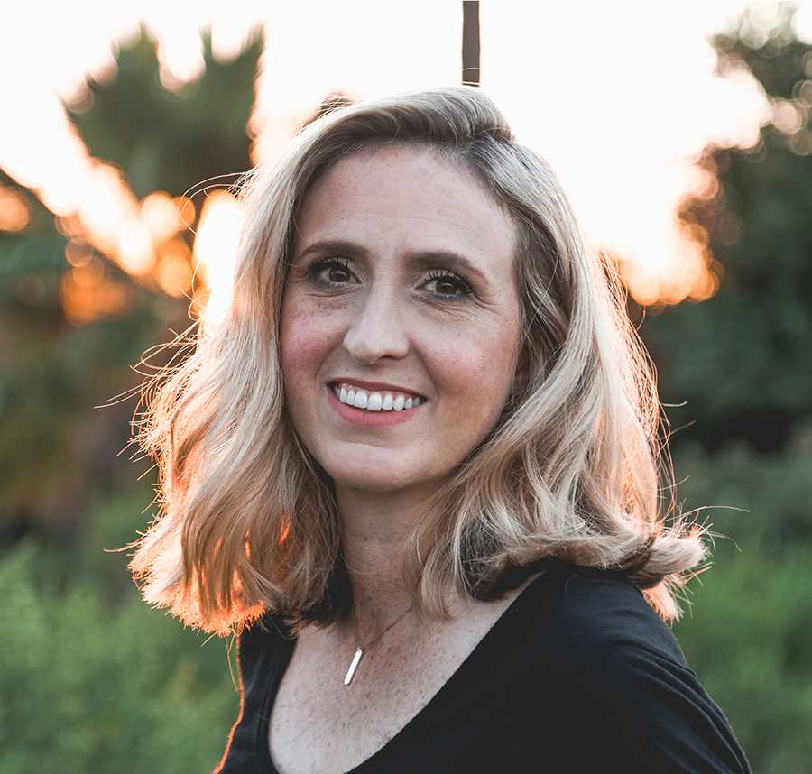 A middle-aged blonde woman smiles at the camera