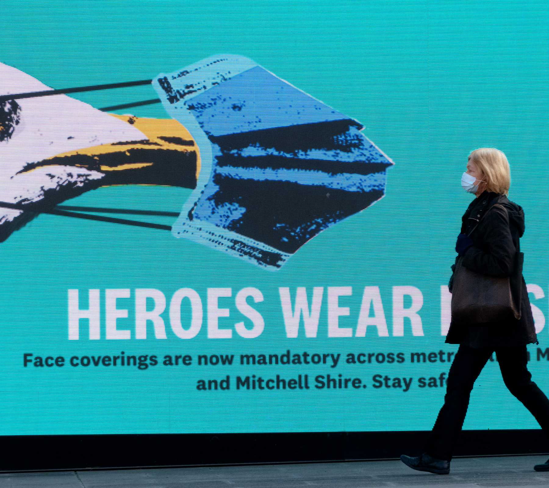 Woman walking past sign for face masks