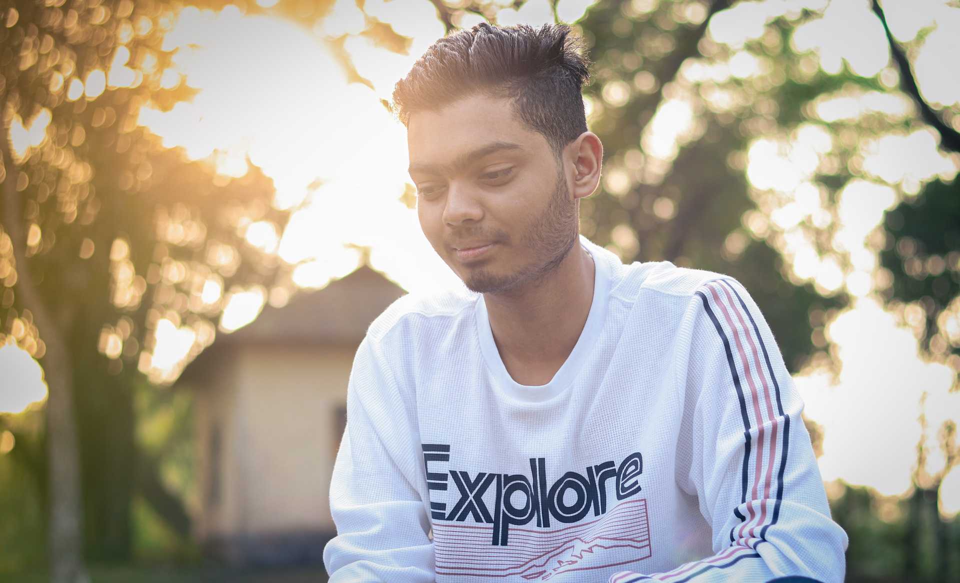 A person sitting down in a white crew neck long sleeve shirt
