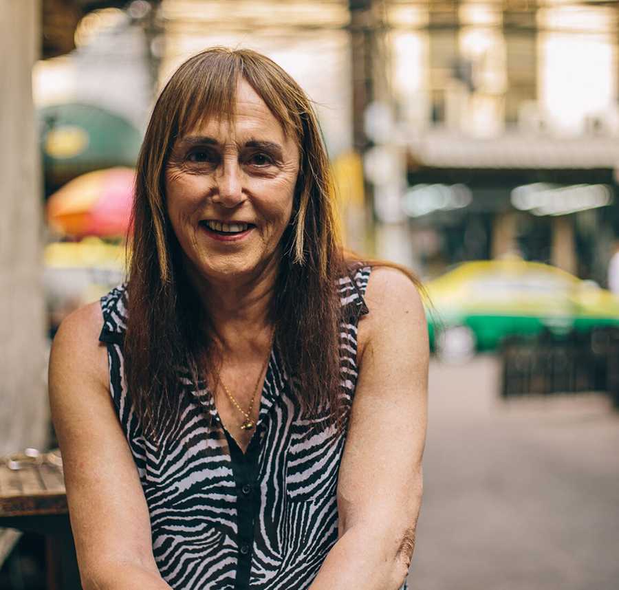 A trans woman sitting at a cafe smiles at the camera.