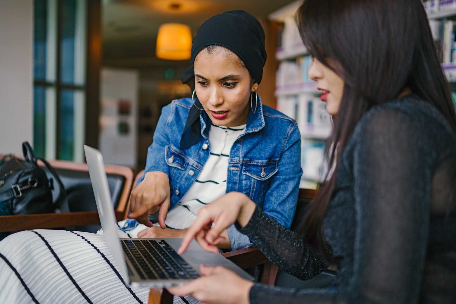 Two women looking and pointing at a laptop