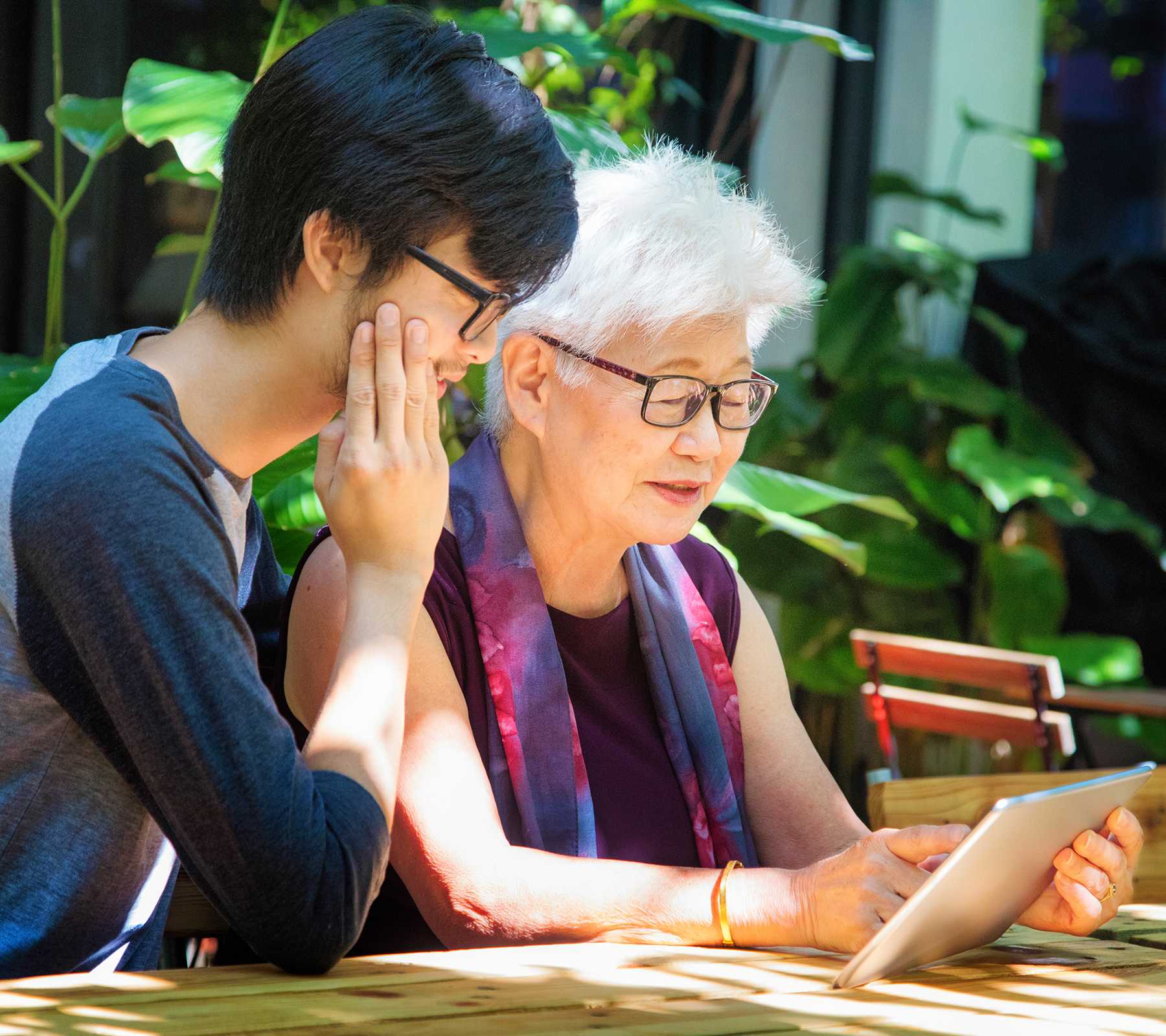 A grandmother and her grandson look at an iPad together.