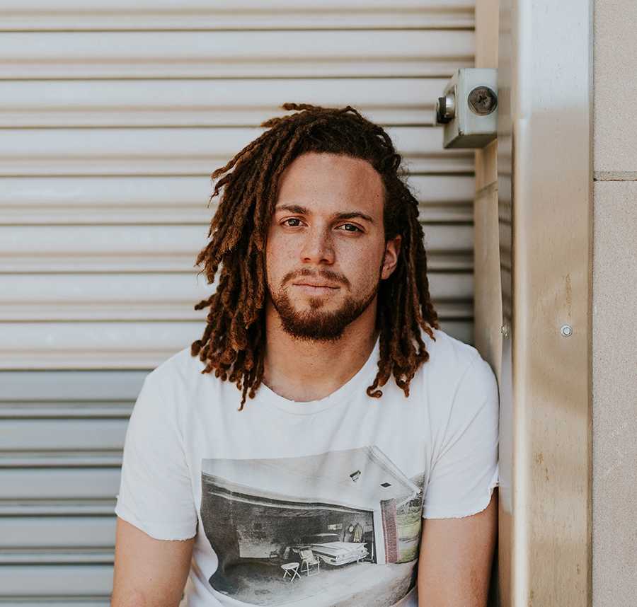 A young man with dreadlocks stares at the camera.